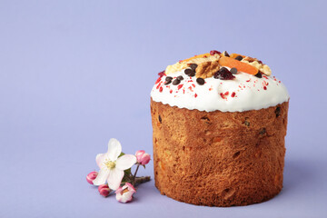 Traditional easter cakes with colorful sprinkles, with eggs and spring flowers on purple background.