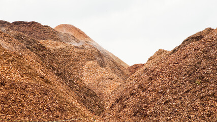 Mountains of wood chips against a gray sky close-up