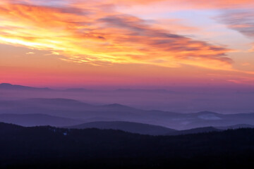  Captivating image of a vibrant sunrise casting colorful hues across the sky, overlooking layers of misty mountains. The scene evokes peace and natural beauty in a serene landscape.