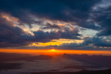 Scenic sunrise above mountain layers and morning fog under a vibrant sky.