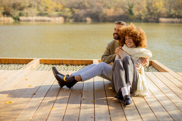 Couple enjoys a cozy moment by the serene lake on a sunny autumn day