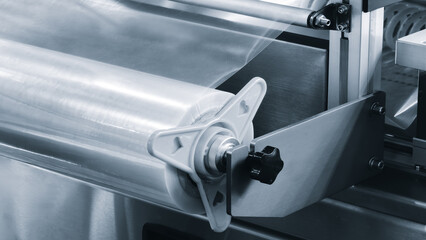 Automatic polyethylene plastic bag production machine with lighting effect. Close-up of the roller of the plastic bag production machine in the light blue scene. product packaging concept