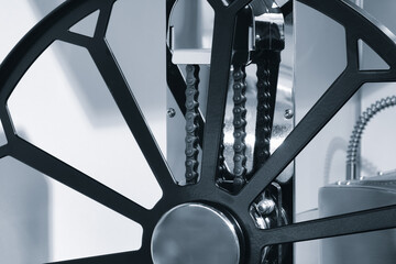 Fototapeta premium A black wheel with a chain on it. The chain is attached to a metal rod, industrial concept background