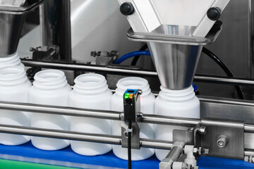 pharmaceutical industry, medicine pills are filling in the  bottle on production line machine conveyor at the medical factory. selective focus