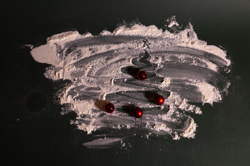 Creative Christmas-themed still-life featuring a tree shape drawn in scattered flour on a dark surface, decorated with small red baubles for a festive, handmade holiday look.