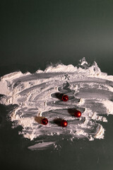 Creative Christmas-themed still-life featuring a tree shape drawn in scattered flour on a dark surface, decorated with small red baubles for a festive, handmade holiday look.