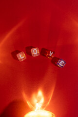 The word “LOVE” formed from small cubes on a red surface, illuminated by warm, soft lighting for a cozy and romantic atmosphere.
