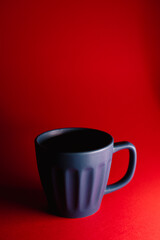 Minimalist still-life featuring a matte blue mug against a vivid red background, with dramatic lighting creating bold contrast and a clean, modern composition.