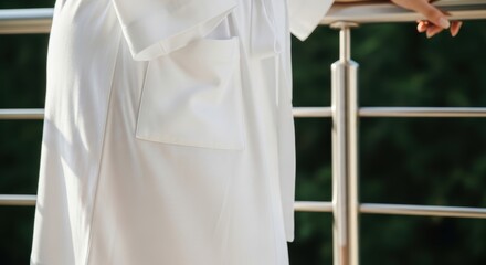Close-up of a white lab coat on a female adult with metal railing background