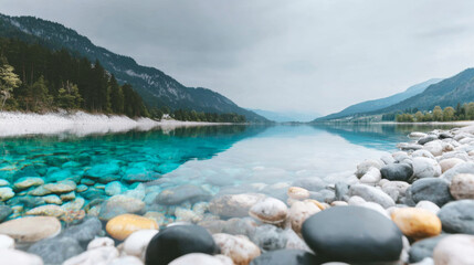 Alpine lake showcasing transparent blue green water, pebbles on the bottom and shore, reflecting cloudy sky and tranquil mountain landscape