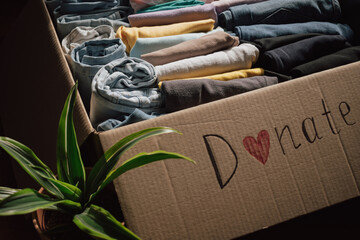 Many clothing items are organised in a donation box with a message promoting kindness and community support