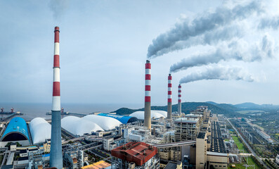 Aerial view of thermal power plant with smoking chimneys near the sea.