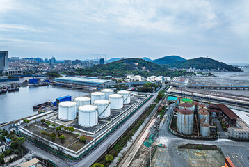 Obraz premium Aerial view of a coastal oil depot with storage tanks and long pier pipeline.