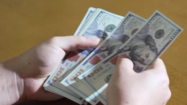 Counting US Dollars Held in Hand Over Table