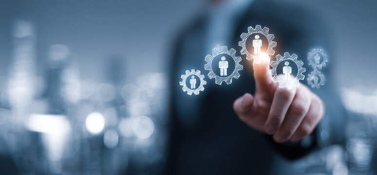 Businessman touching virtual screen with gears and human icons, representing technology and innovation in management. scene conveys sense of progress and connectivity - Powered by Adobe