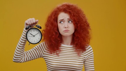 Woman with Red Hair Holding Alarm Clock on Yellow Background.