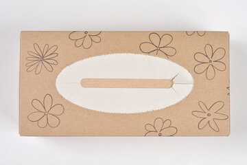 An overhead view of a closed rectangular tissue box made of brown Kraft paper with a simple floral line art design on a white background
