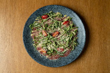 Bright colors of fresh greens and cherry tomatoes create a vibrant salad on a rustic plate. The sunny afternoon setting enhances the meal's appeal, inviting everyone to share a healthy experience