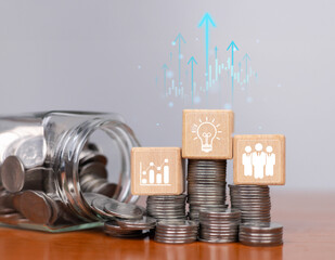 A concept image showing stacked coins with wooden blocks symbolizing growth, innovation, and...