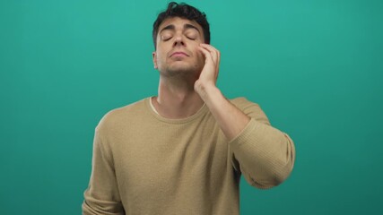 Man forehead touching background while guy young hispanic green backdrop male looks stressed.
