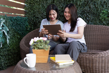 Shared Moment: Two friends, engrossed in the digital world, share a moment of connection while relaxing on a cozy patio, enhanced by natural greenery and subtle lighting.