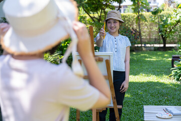 Artistic Moments in Garden: Two individuals engaged in a creative pursuit, one sketching on an easel in a garden setting, radiating the joy of artistic expression and collaborative creativity.