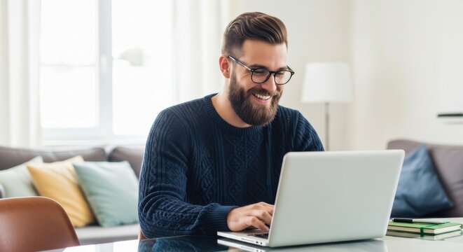 Happy bearded man working on laptop at home