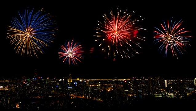 Colorful fireworks explode over a city skyline at night