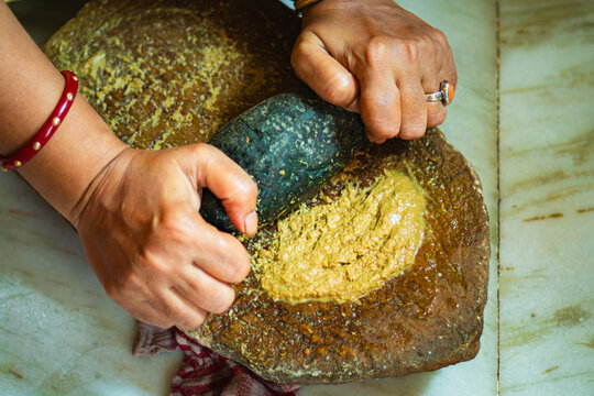 Indian woman grinding spices on traditional sil batta stone grinder