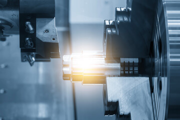 Close up scene the CNC lathe machine finish cut the metal shaft parts in the blue tone scene with lighting effect.