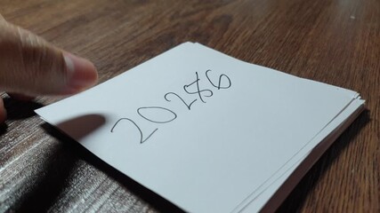 The year “2025” being crossed out and rewritten as “2026,” a simple symbolic moment representing new year transition, change, and forward-looking optimism.