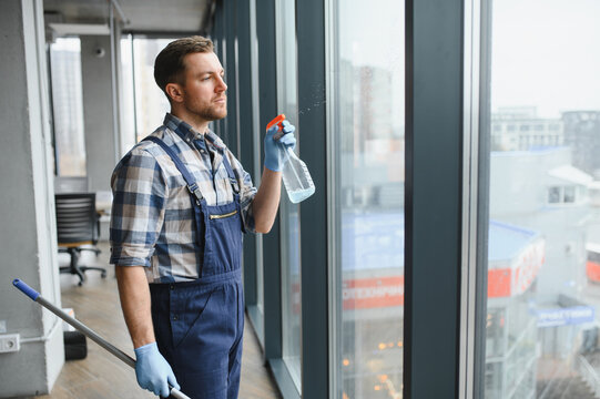 Professional cleaning service worker washing windows in modern office building