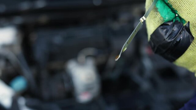 Close-up of a car engine dipstick pulled out, showing the oil level