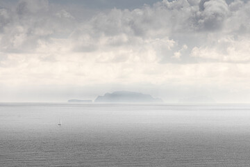 Dramatic volcanic cliffs and serene ocean view at Ponta de S&atilde;o Louren&ccedil;o, Madeira Island, Portugal &ndash; panoramic coastal landscape with sailboats, hiking trails, and wild natural beauty.
