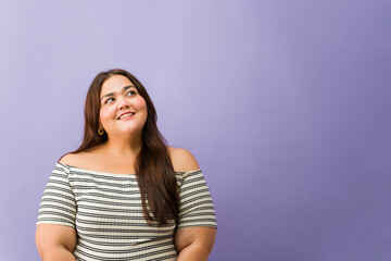 Plus size woman smiling looking up daydreaming
