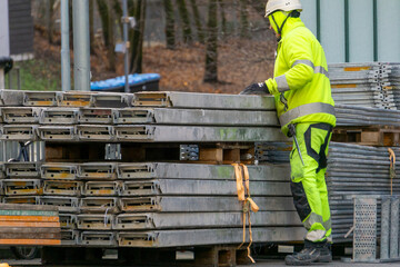 Construction Worker Stacking Metal Scaffolding Decks Hi Vis Gear Site Logistics