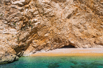 Rocky cliff overlooking secluded beach with turquoise water
