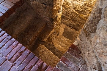 Ancient stone spiral staircase with brick walls in historic ruins