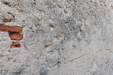 Textured surface of an old weathered brick wall with crumbling plaster