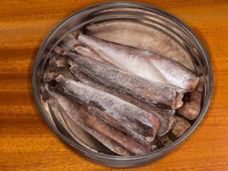 Frozen Argentine hake carcasses in big stainless steel kitchen bowl
