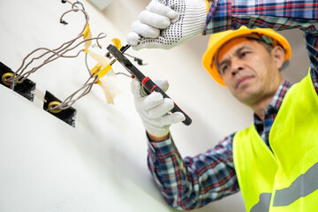 Electrical technician performing wiring installation construction site professional work indoor environment close-up view skill application