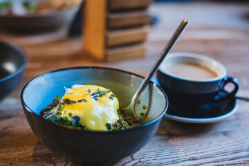 Poached egg beaten with buckwheat and herbs stands on the table in a dark deep bowl. High quality photo