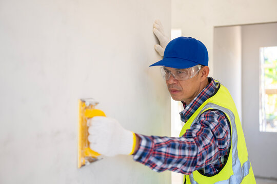 Construction worker applying finishing touches modern interior photography indoor close-up craftsmanship in action