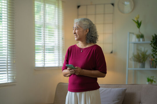 relaxed senior woman stays connected with social media on her smartphone at home - Powered by Adobe