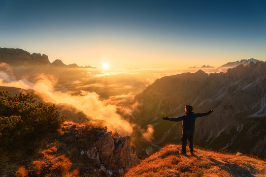 Majestic view of male tourist standing with sunrise over mountain ridge in Cadini di Misurina, Dolomites, Italy