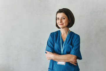 Portrait of smiling, confident Caucasian woman doctor wearing blue uniform and badge, isolated on...
