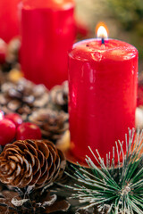 Red candles and pinecones create a cozy atmosphere during the holiday season