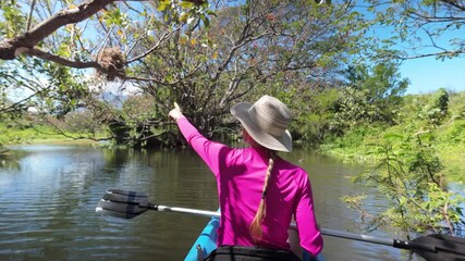 Mature woman enjoys kayaking in the serene Riolstian swamp on Ometepe Island, surrounded by vibrant nature and peaceful waters.