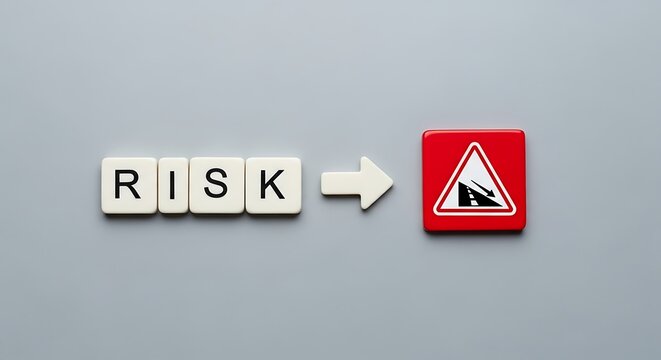 Scrabble tiles spelling risk pointing to a red warning sign indicating a falling rock hazard on gray background