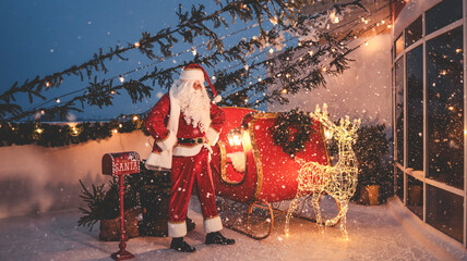 Santa Claus stands beside his sleigh in a snowy Christmas scene